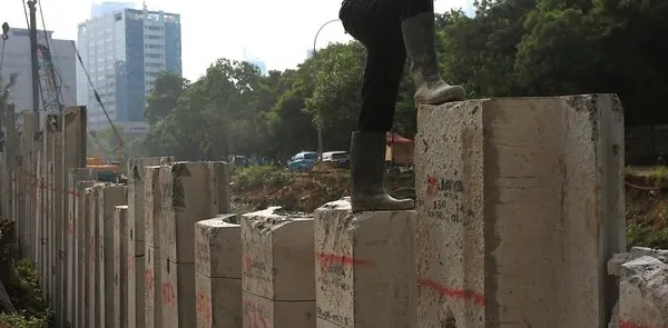 Para pekerja menyelesaikan proyek penguatan tanggul turap di kawasan Kuningan, Jakarta Selatan, Selasa (21/4/2026).