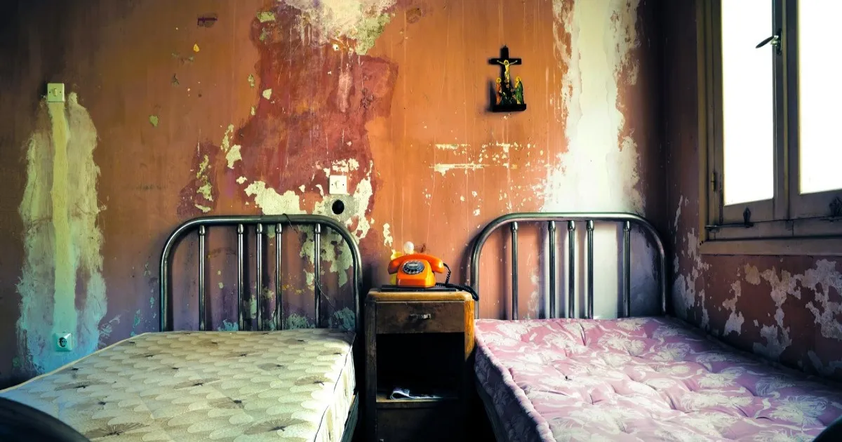 Ilustrasi hotel terbengkalai dengan tempat tidur kotor dan telepon antik di atas meja